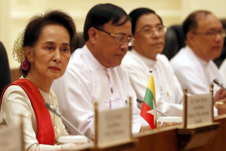 Myanmar leader Aung San Suu Kyi sitting at a conference with several colleagues form the National League for Democracy.