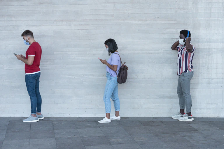 A line of masked people on their phones