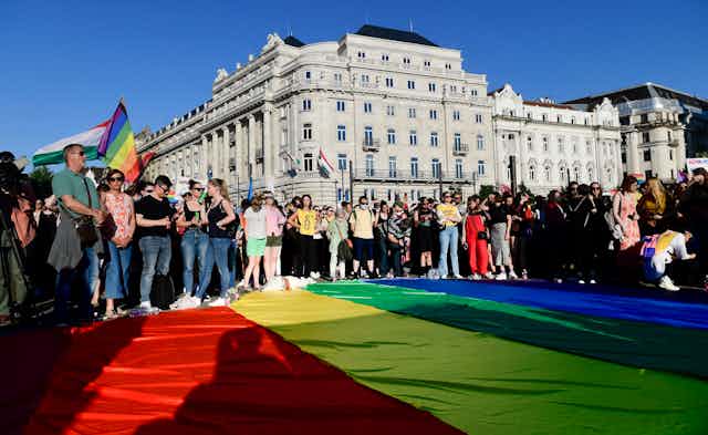 Protesters gather around a large Pride flag in front of the parliament building in Budapest