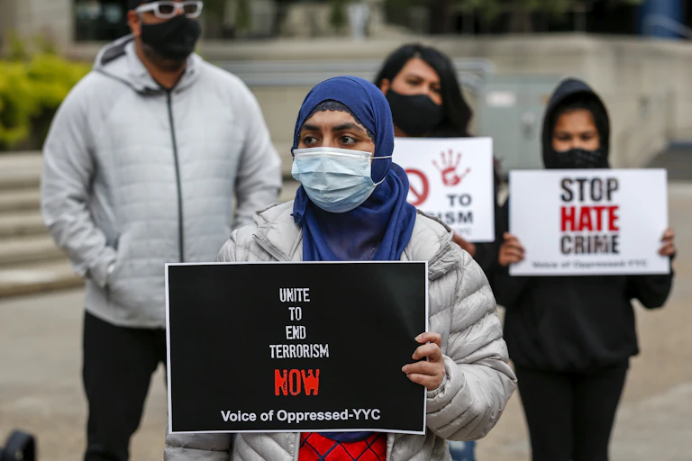 demonstrators holding signs like UNITE TO END TERRORISM NOW and STOP HATE CRIME