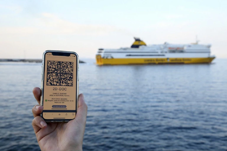 Une femme montre le QR code de son test PCR, devant un bateau Corsica Ferries au départ de Bastia, le 9 juin 2021.