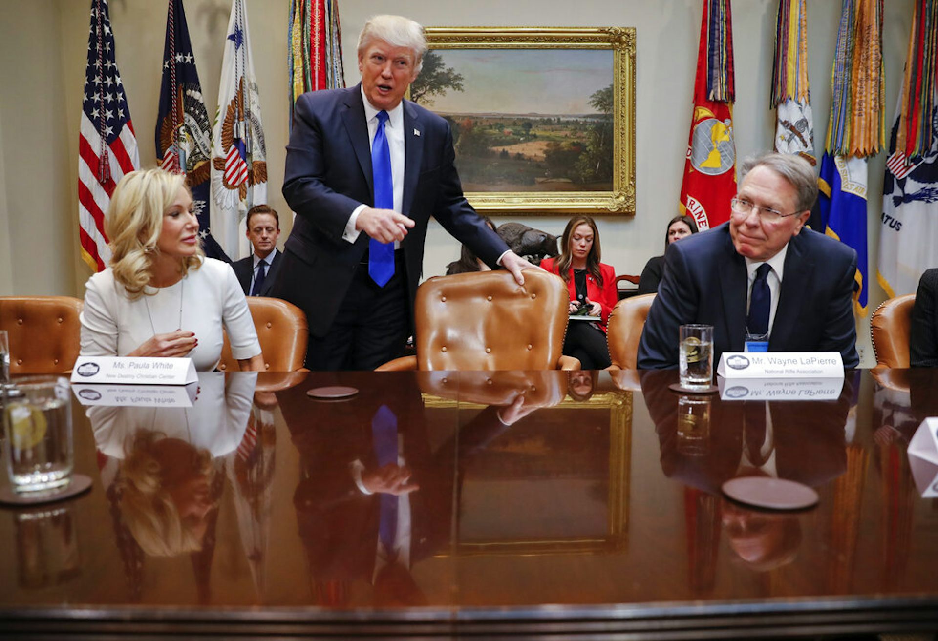 President Donald Trump takes his seat next to National Rifle Associations (NRA) Executive Vice President and Chief Executive Officer Wayne LaPierre, right, and Pastor Paula White, left, of the New Destiny Christian Center, at a 2017 White House meeting.