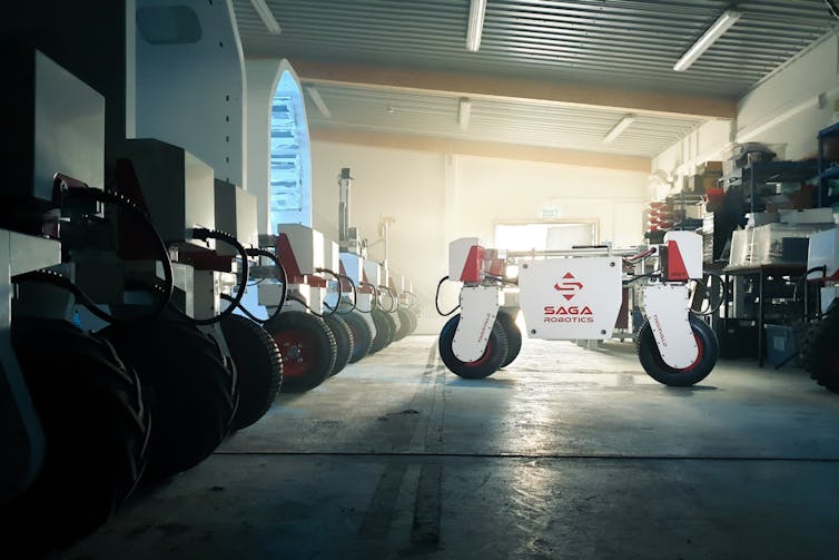 Robot a quattro ruote in un garage accanto a una fila di altri robot