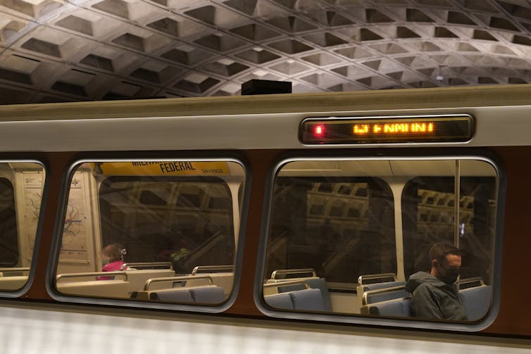 Subway car with two riders.