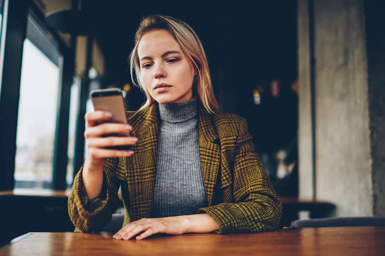 A young woman looks at her smartphone.