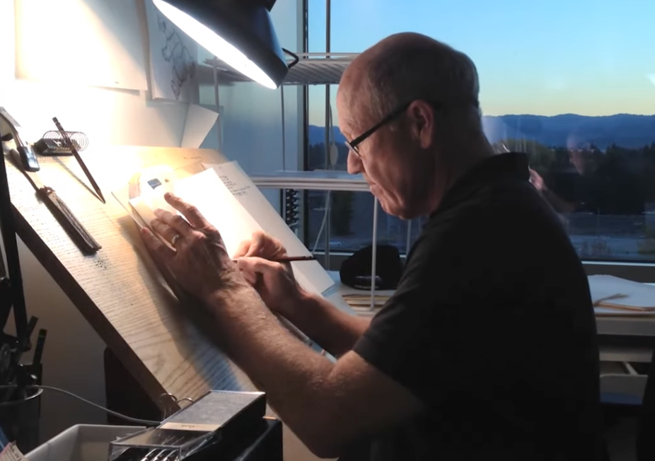 Glen Keane sketching on paper with a light shining over it