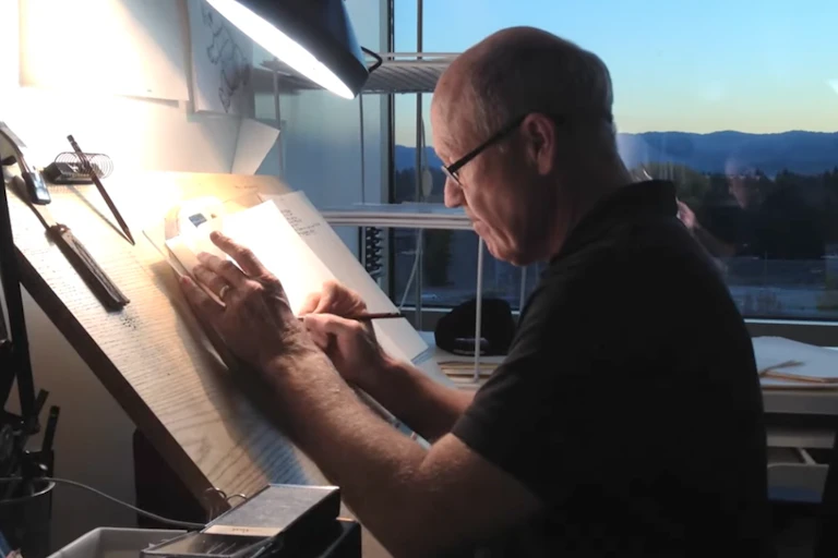 Glen Keane sketching on paper with a light shining over it
