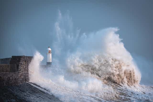 A lighthouse is buffeted by large waves during a storm.