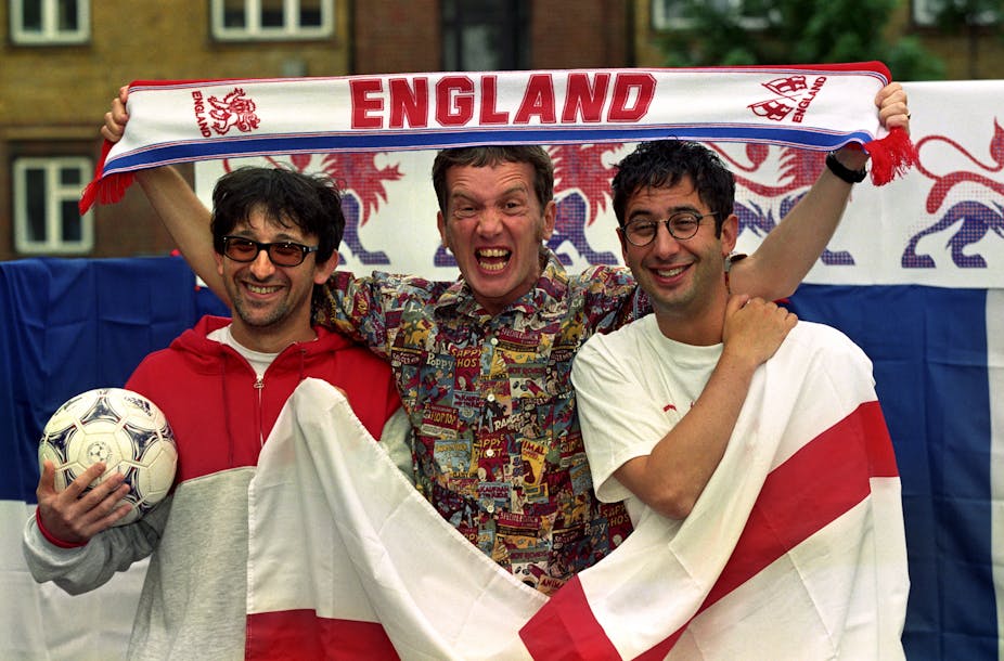 Three men holding the English flag, a football and an England scarf.