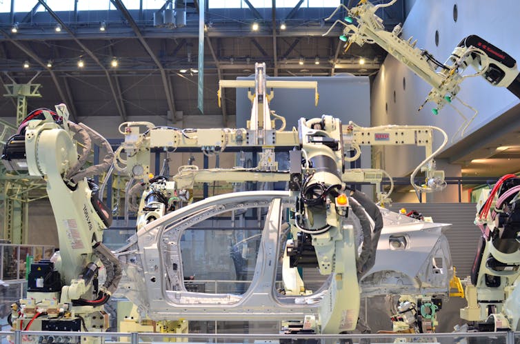 Robotic arms in factory assemble a car body shell.