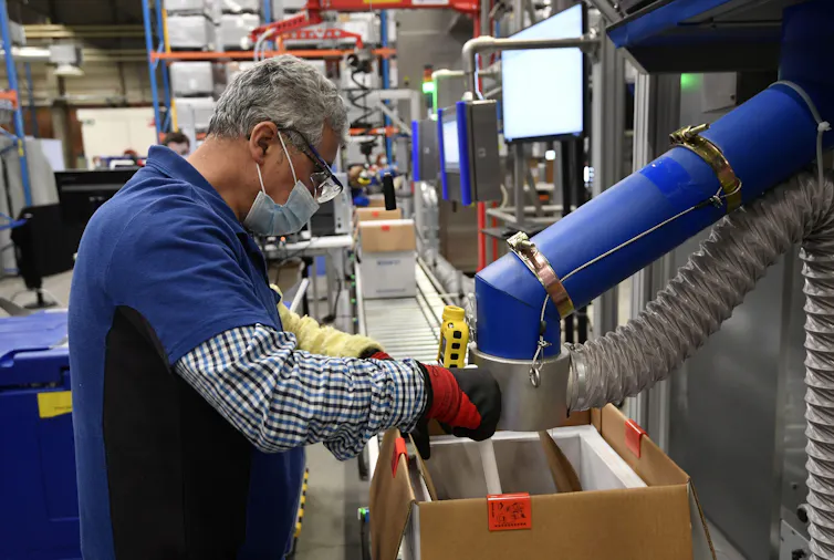 Un hombre con mascarilla trabajando en una máquina en la fábrica de vacunas de Pfizer en Bélgica