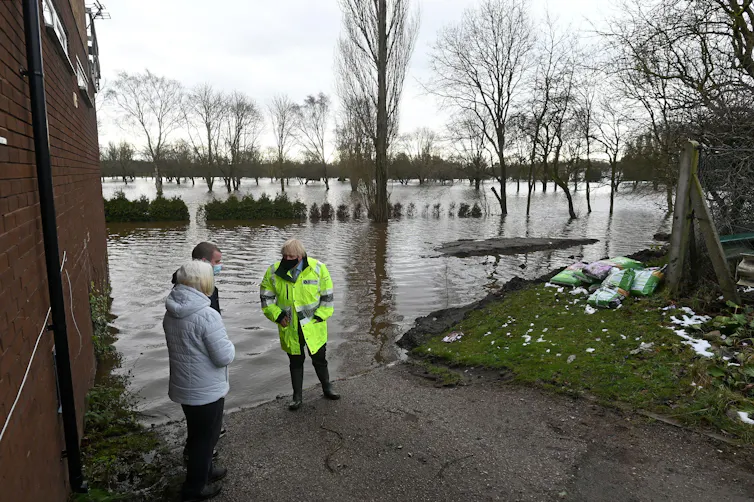 Boris Johnson talks with locals at the side of a flooded area.
