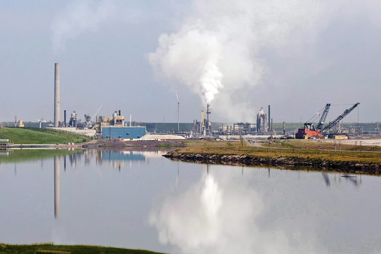 An oilsands facility is reflected in a tailings pond