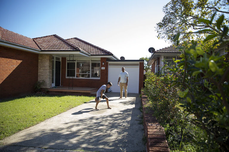 A child and parent are playing in their home's driveway.