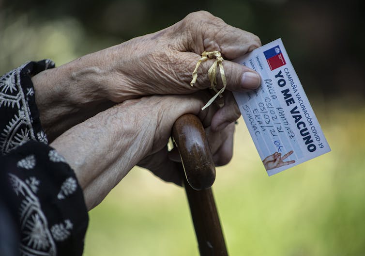 Elderly lady holds her vaccination card in Chile
