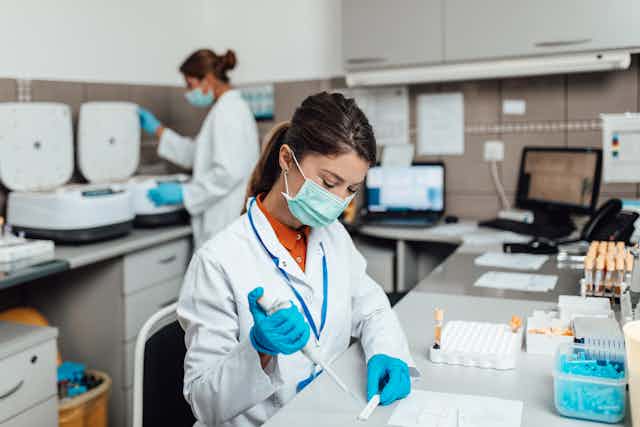 Lab technicians work while wearing masks. 