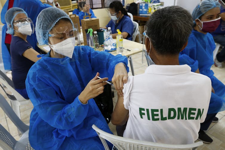 A health worker vaccinates a citizen with the Sinovac COVID-19 vaccine in the Philippines