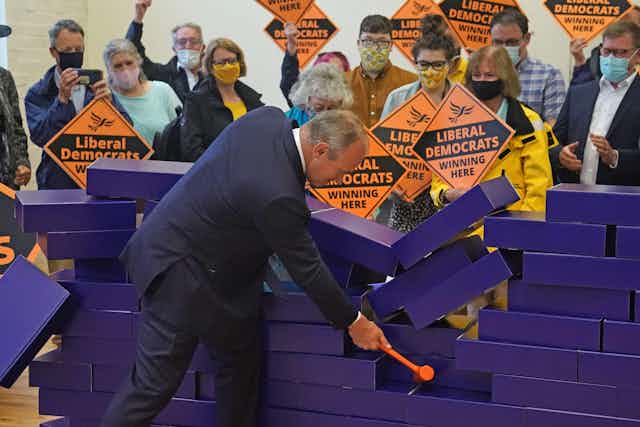 Lib Dem leader Ed Davey uses a mallet to demolish a wall of blue bricks meant to represent the Conservatives' 'blue wall' in southern England.