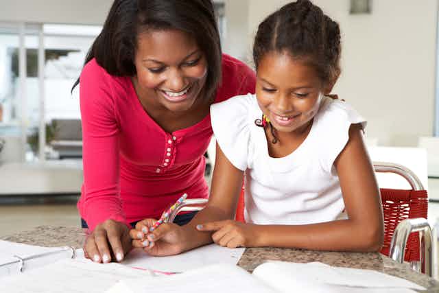A happy mother looking over her daughter's schoolwork.