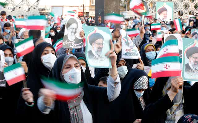 Iranian women wave flags and hold up pictures of the newly elected president Ebrahim Raisi, an arch conservative.