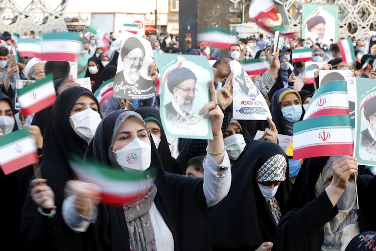 Iranian women wave flags and hold up pictures of the newly elected president Ebrahim Raisi, an arch conservative.