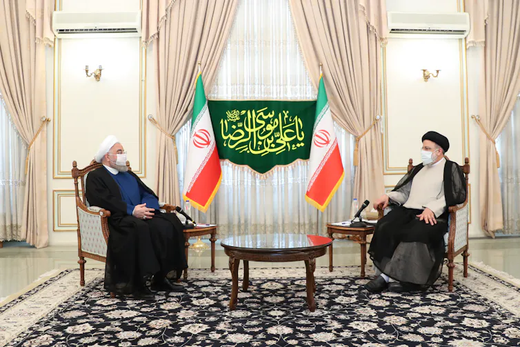 Iranian leaders sat opposite each other, wearing face masks.
