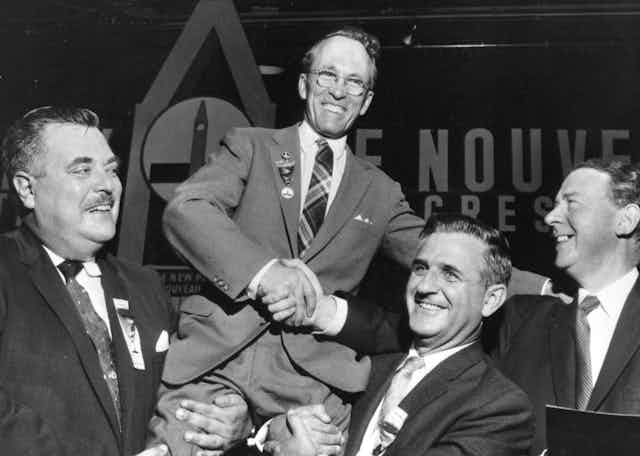Tommy Douglas is held up by supporters in a black and white photo.