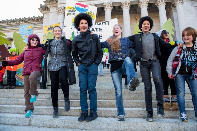 Young people stand on the steps of the Capitol building in Olympia, Washington