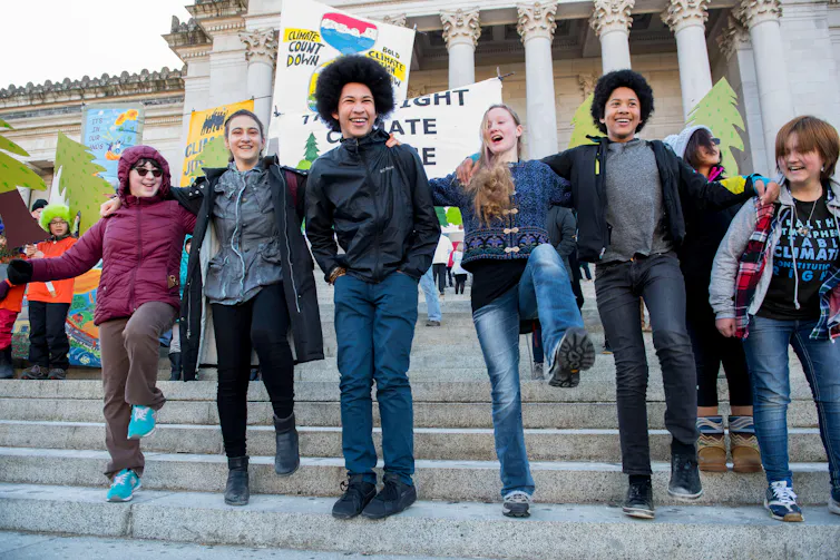 Young people stand on the steps of the Capitol building in Olympia, Washington