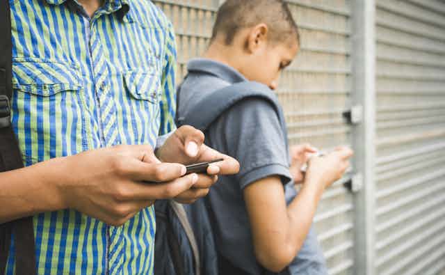 Two young people texting on their mobile phones