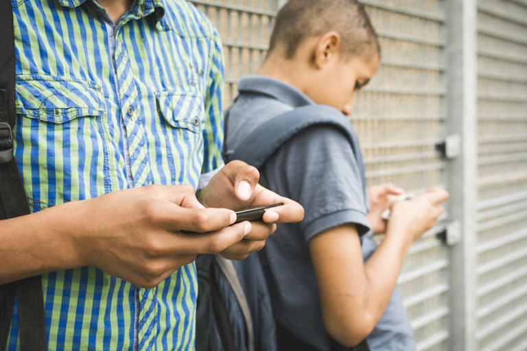 Two young people texting on their mobile phones