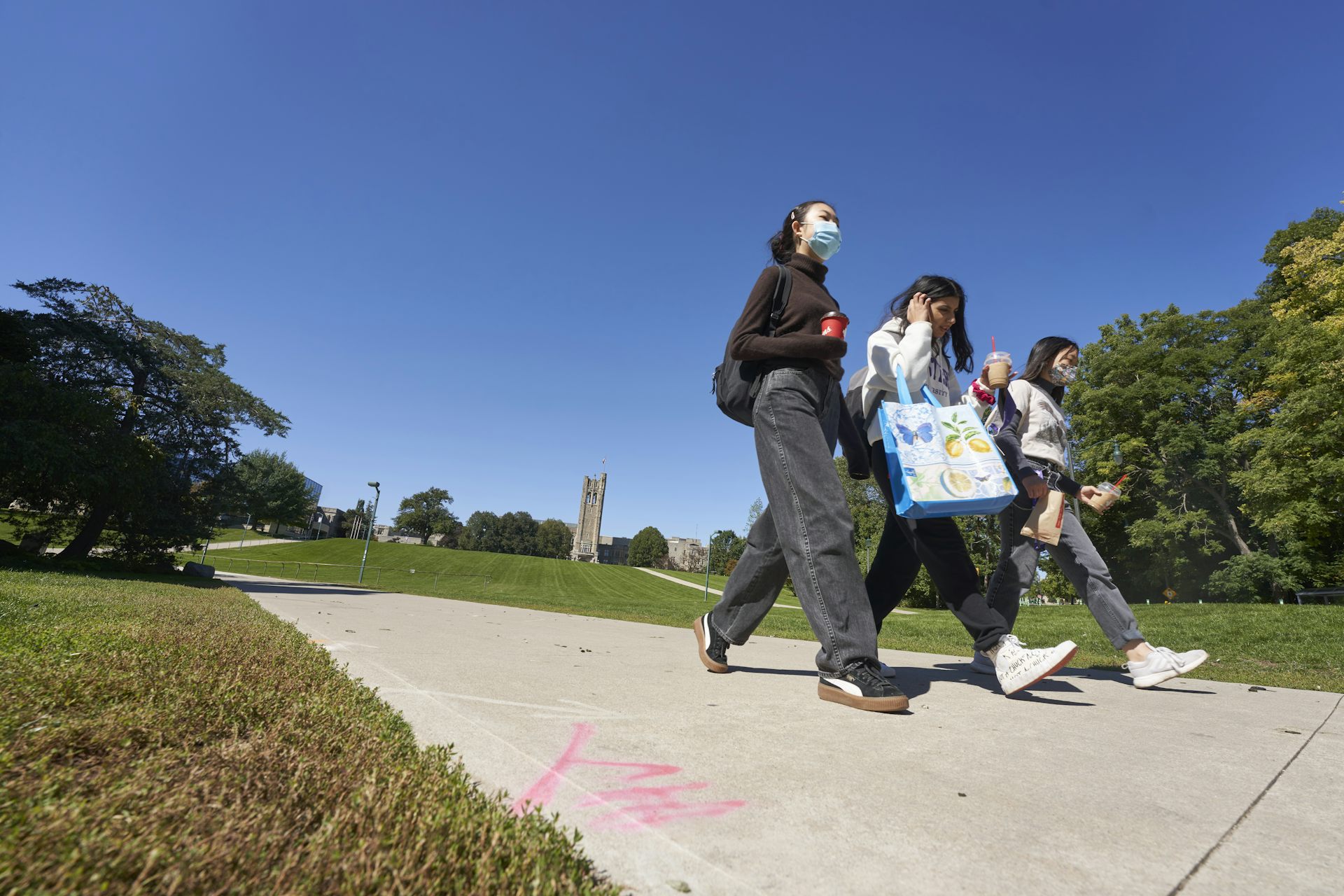 Students walking through a campus, some wearing face masks.