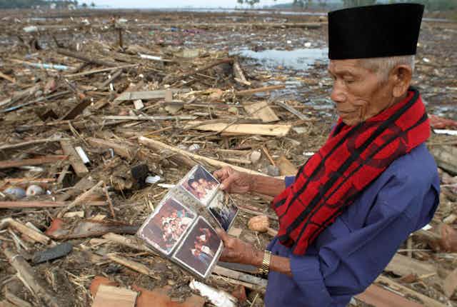 A man looks at a photo album in a destroyed village.
