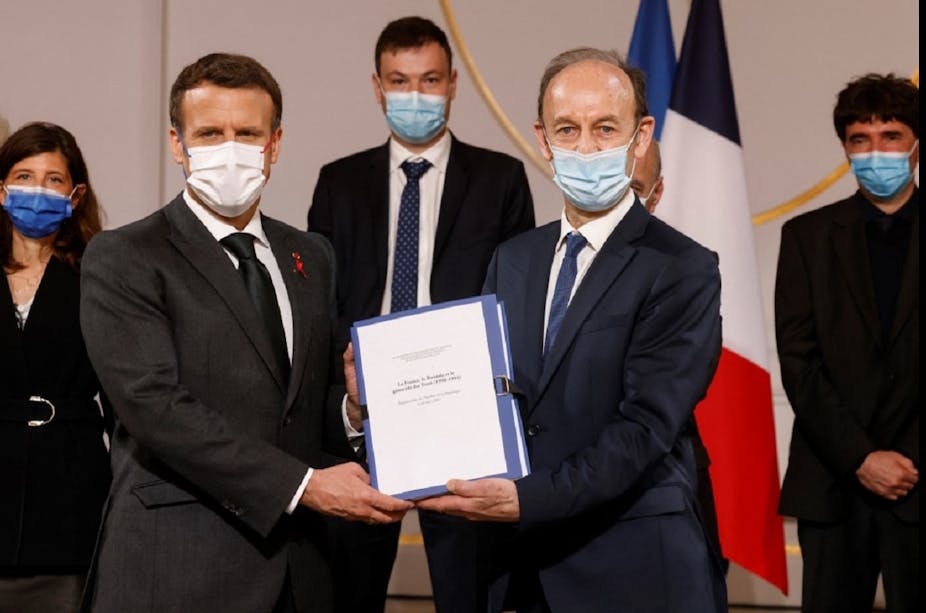 Emmanuel Macron et Vincent Duclert, dirigeant la commission d'historiens sur le Rwanda, tiennent le rapport sur les archives déclassifiées à la demande du président, le 26 mars 2021, dans la salle des fêtes de l'Élysée.