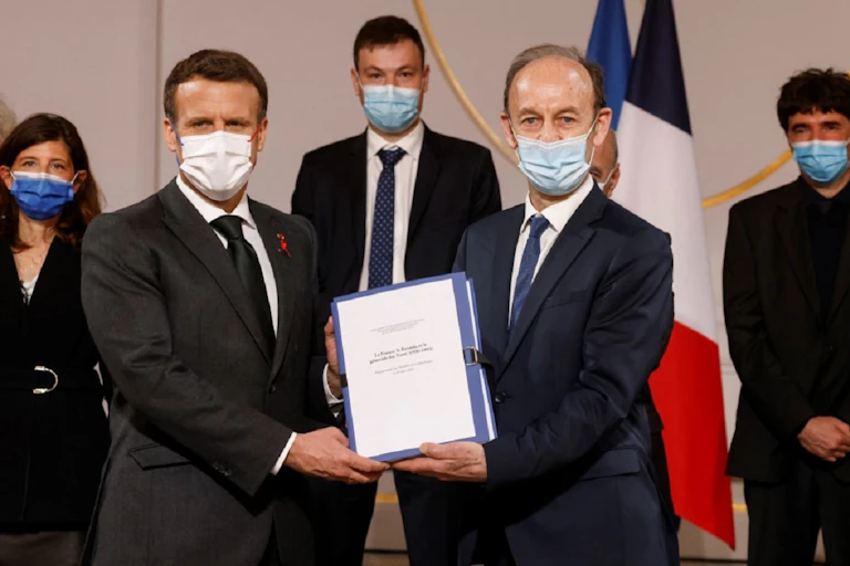 Emmanuel Macron et Vincent Duclert, dirigeant la commission d'historiens sur le Rwanda, tiennent le rapport sur les archives déclassifiées à la demande du président, le 26 mars 2021, dans la salle des fêtes de l'Élysée.