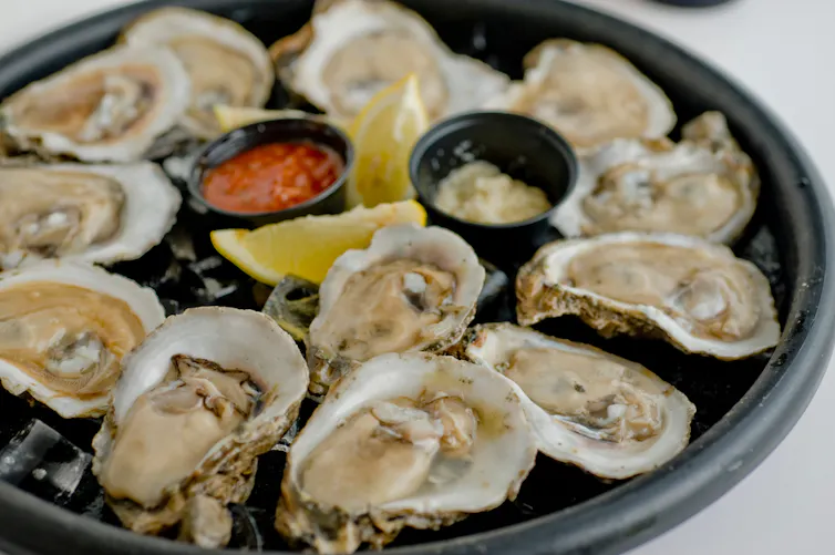 a dish of oysters served with sauces and lemon