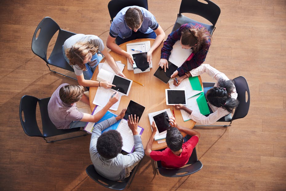 overhead view of students on digital devices around a table