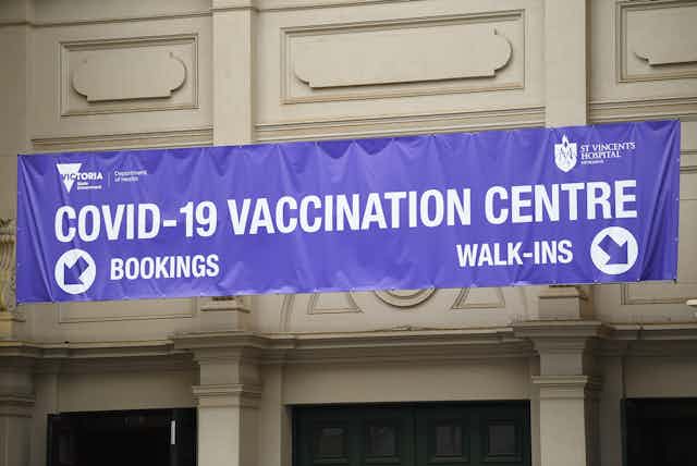 A purple sign reading 'COVID-19 VACCINATION CENTRE' in Melbourne.