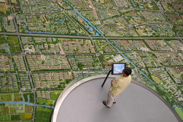 man stands inn front of screen on a platform looking out over a city