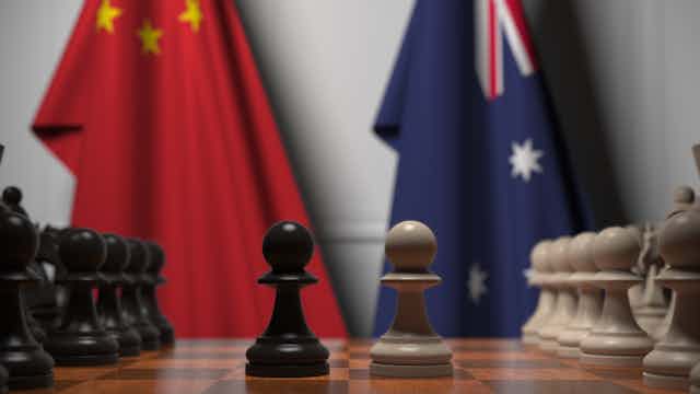 A chessboard, with an Australian and a Chinese flag in the background