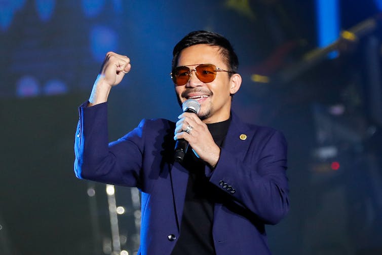 Filipino boxing champion Manny Pacquiao flexes his bicep while making a speech, Manila 2019.