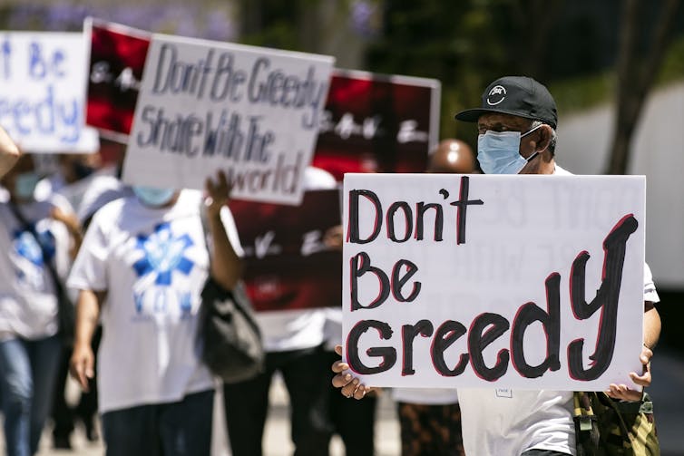 Protestors in California holding placards calling for the US to share vaccines