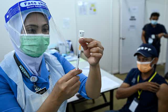A nurse loading a syringe with COVID-19 vaccine fluid