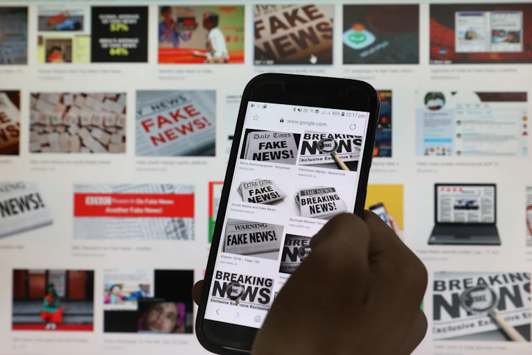 A hand scrolls the screen of a mobile phone while loading information on how to counter 'fake news'.