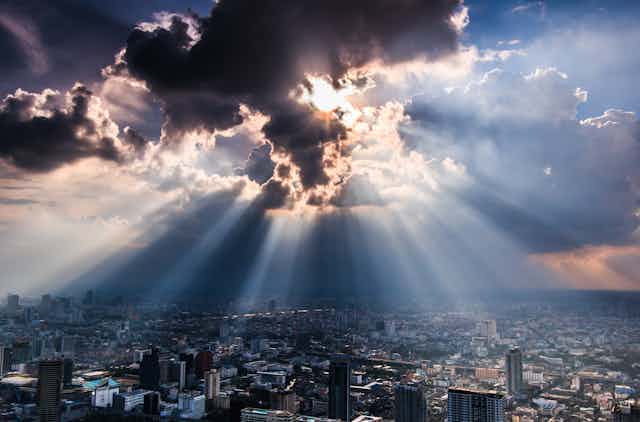 Clouds blocking sunlight from reaching a city