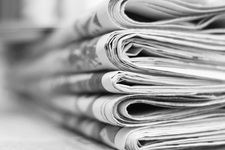 A pile of newspapers, folded, black and white