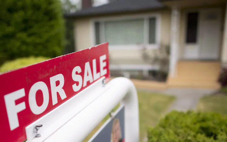 A 'For Sale' sign is pictured in front of a house