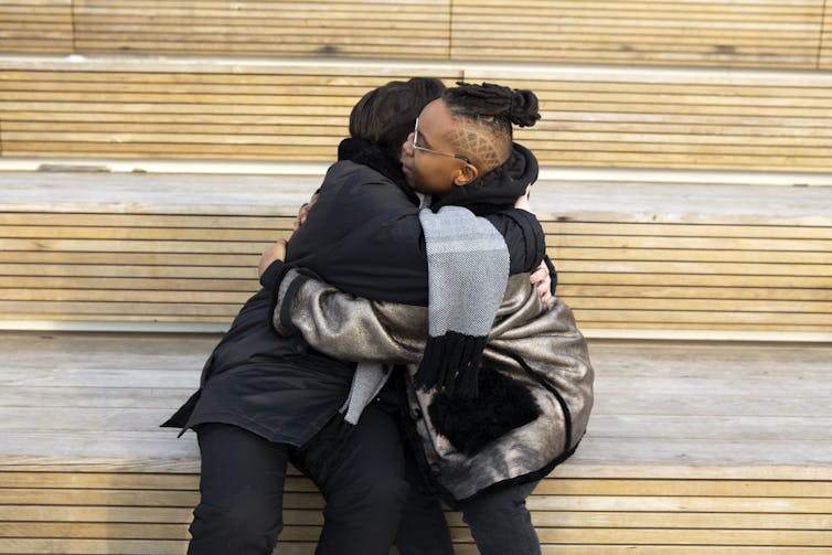 Two people sit hugging on steps