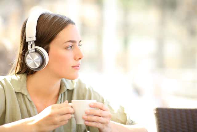 Young women with headphones on listens pensively
