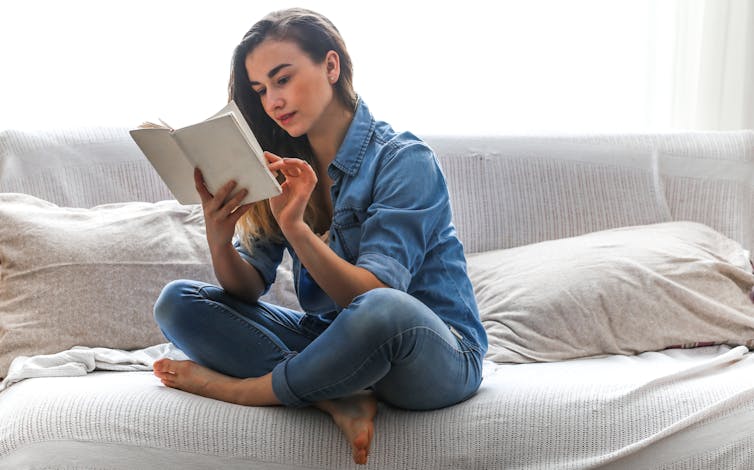 Girl reading book on the couch.